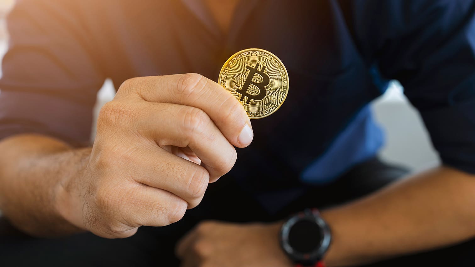 golden bitcoin in a businessman hand in the office with soft foc